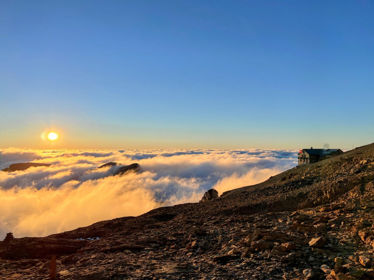 Auf der Hütte angekommen beziehen wir unser Zimmer (es hat mehrere Schlafsäle) und gönnen uns den obligatorischen Hüttenkuchen. Wir sind froh, dass wir die Etappe unterbrochen haben und heute nicht mehr absteigen müssen. Immer wieder schauen wir aus dem Fenster und plötzlich lichtet sich der Nebel und wir haben einen strahlend blauen Himmel vor uns - wow! Sofort werden die Schuhe nochmal angezogen und wir gehen los in Richtung Gletscher. Diesen haben wir nach ungefähr 10 Minuten erreicht und 2 aus unserer Gruppe sind zum ersten Mal auf einem Gletscher. Wir wagen uns ein paar Meter aufs Eis und hören dem Gluckern des Gletscherbaches zu.